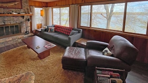 Una sala de estar acogedora con chimenea, un sofá, un sillón de cuero y una mesita de centro.