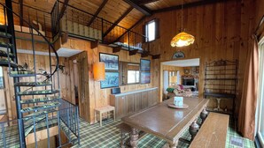 Un interior de madera con una escalera, una zona de comedor y una chimenea.