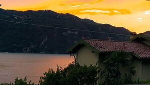 Un balcón con vista a un atardecer sobre el agua y colinas.