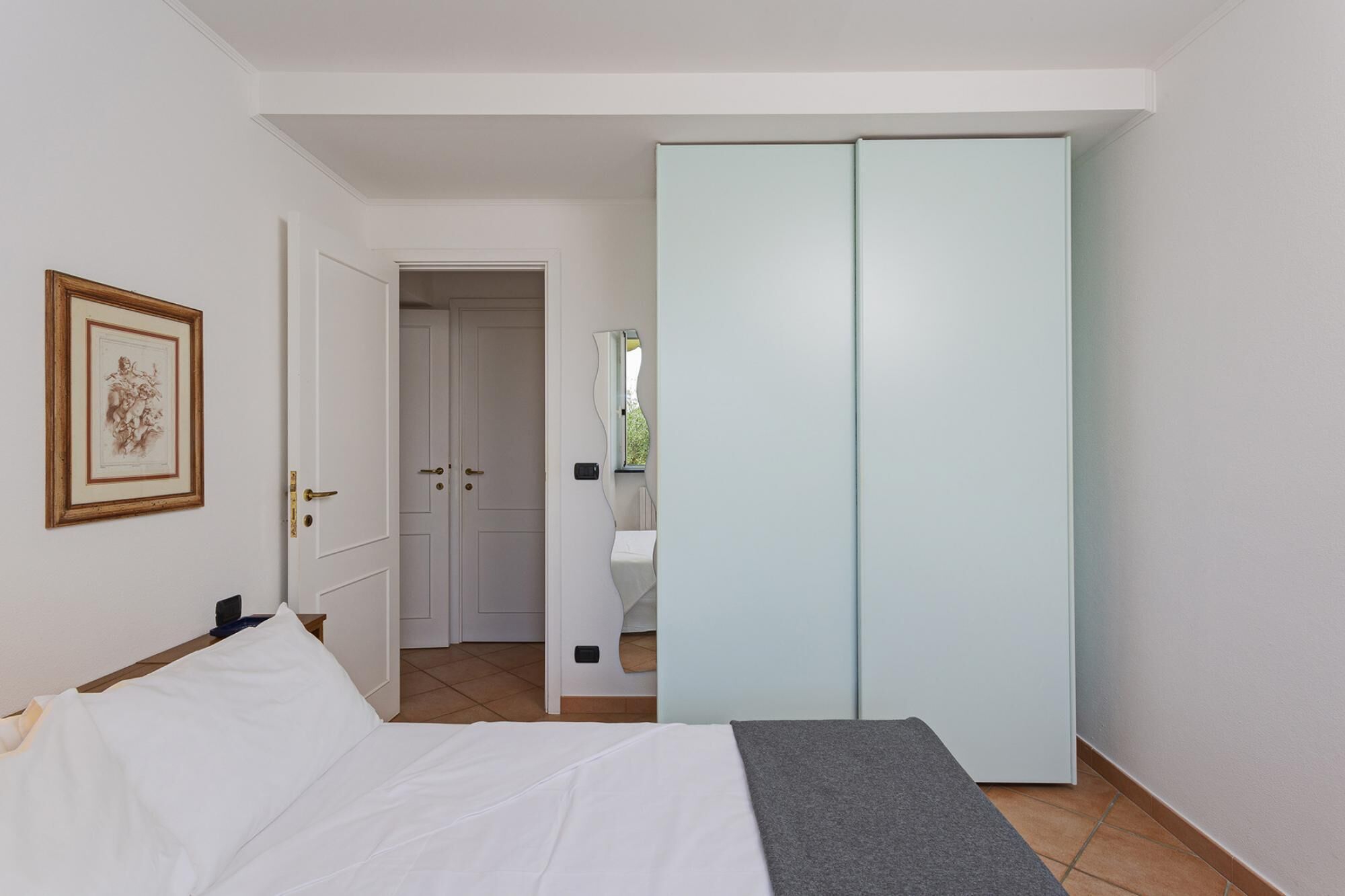 Een slaapkamer met een bed, een garderobe en een deur naar een badkamer.