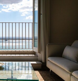 A room with a view of the sea through a balcony railing, a sofa, and a glass coffee table. - Seaview Design Home 21 by Wonderful Italy (Syracuse)