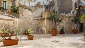 An outdoor courtyard with terracotta planters, a wooden table, and chairs. - Studio Dione 130 by Wonderful Italy (Syracuse)