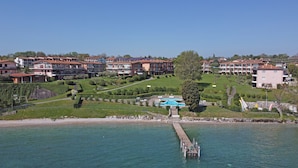 A coastal hotel with multiple buildings, a swimming pool, and a dock extending into the water. - San Sivino 55 con Piscina by Wonderful Italy (Manerba del Garda)