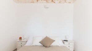 A minimalist bedroom with a bed, two bedside tables, and a nightstand. - Villa Tranquillo 1876 by Wonderful Italy (Ostuni)