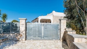 A gated entrance with a stone pathway leading to a building with a white facade and stone accents. - Villa Tranquillo 1876 by Wonderful Italy (Ostuni)