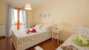 A bedroom with a bed, bedside tables, a window with curtains, and wall art. - Baglio Degli Ulivi 3 by Wonderful Italy (Sirmione)