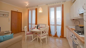 A compact living space with a dining area, kitchenette, and a sofa. - Baglio Degli Ulivi 3 by Wonderful Italy (Sirmione)