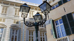 Eine Straßenlaterne mit aufwendiger Metallverzierung und ein Gebäude im Hintergrund, das klassische Architektur aufweist.