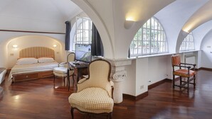 Ein geräumiges Schlafzimmer mit einem großen Bett, einem Schreibtisch und zwei Stühlen. Das Zimmer verfügt über hohe Decken und große Fenster.