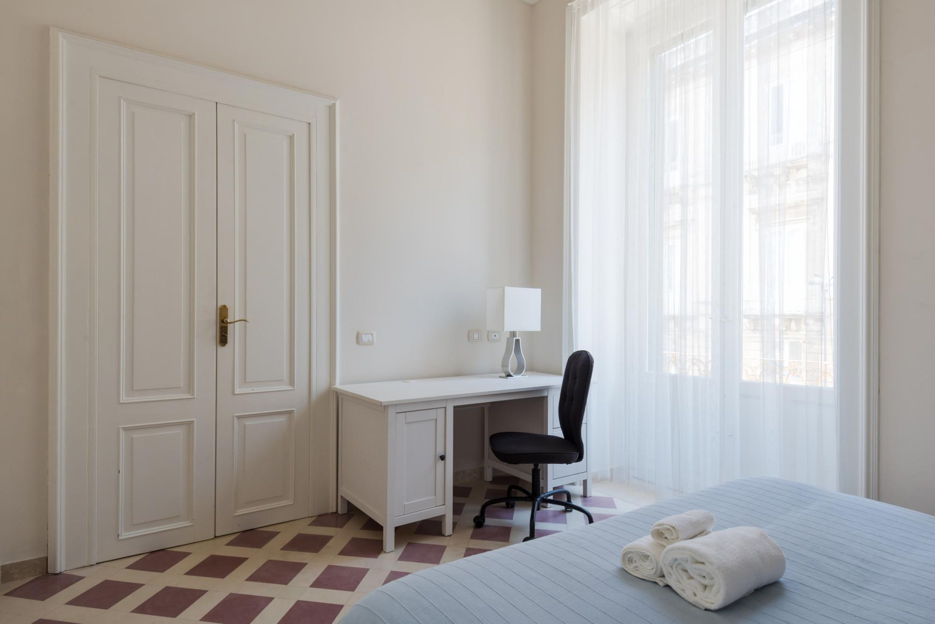A bedroom with a bed, a desk, a chair, and a wardrobe.