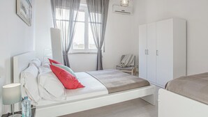 A modern bedroom with a bed, bedside table, lamp, and wardrobe. - Casa Aglian con Vista by Wonderful Italy (Cefalù)