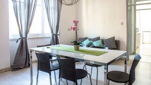 A modern dining area with a white table, black chairs, a potted orchid, and a sofa with cushions. - Casa Aglian con Vista by Wonderful Italy (Cefalù)