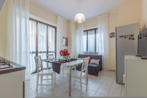A modern kitchen with a dining area, large windows, and a refrigerator.