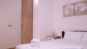 A neatly made bed with folded white towels, a bedside table with a lamp, and a wall-mounted artwork of white flowers. - Design Apartment Alle due Torri by Wonderful Italy (Bologna)
