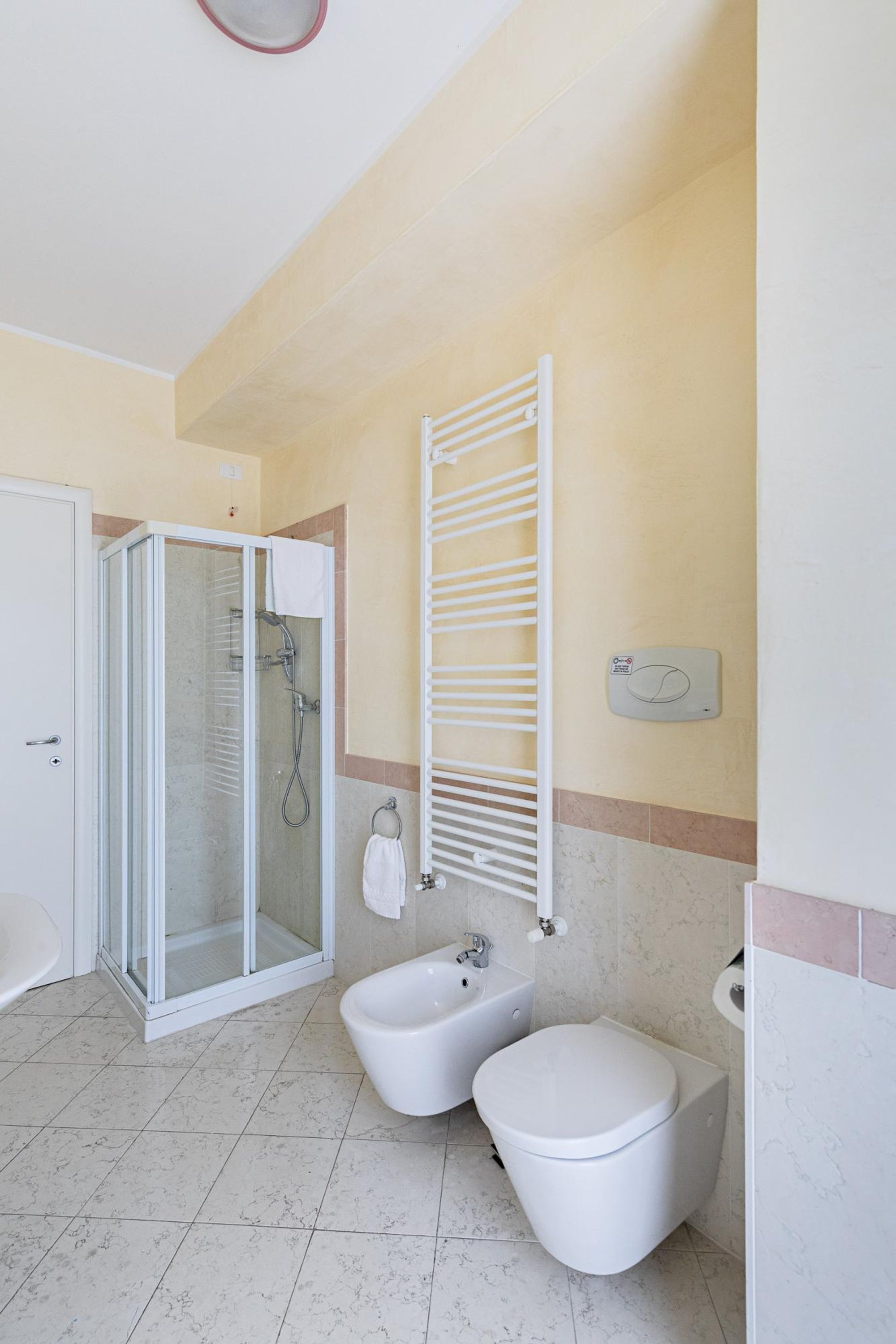 A bathroom with a glass-enclosed shower, a white sink, and a toilet.