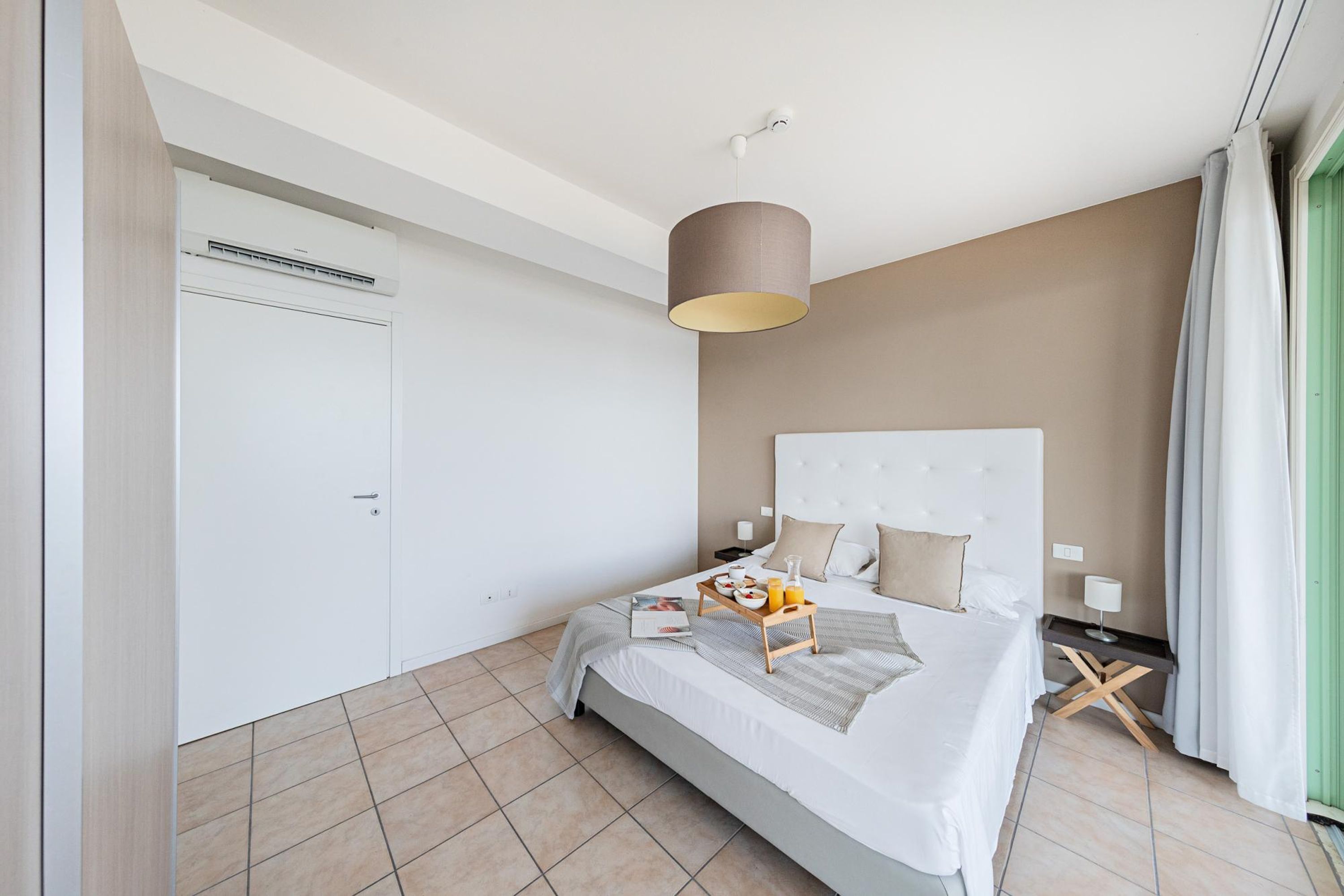 Een moderne hotelkamer met een groot bed, een nachtkastje, een lamp en een ontbijttray.