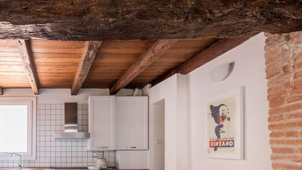 Una cocina con armarios blancos, una mesa de comedor de madera y una pared de ladrillo.