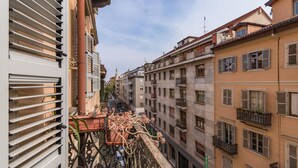 A narrow street with buildings on both sides, featuring balconies with plants and outdoor furniture. - S Salvario Family Apartment by Wonderful Italy (Turin)