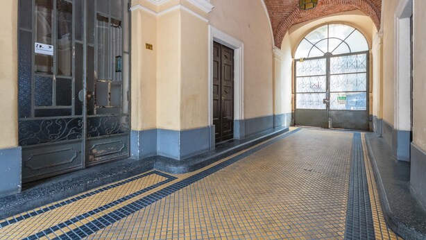 A hallway with a tiled floor, a large arched window, and a door with a sign. - S Salvario Family Apartment by Wonderful Italy (Turin)
