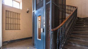A staircase with ornate black railings and a blue elevator door. - S Salvario Family Apartment by Wonderful Italy (Turin)