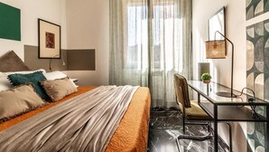 Ein Hotelzimmer mit Bett, Schreibtisch, Stuhl und einem Fenster mit Vorhängen.