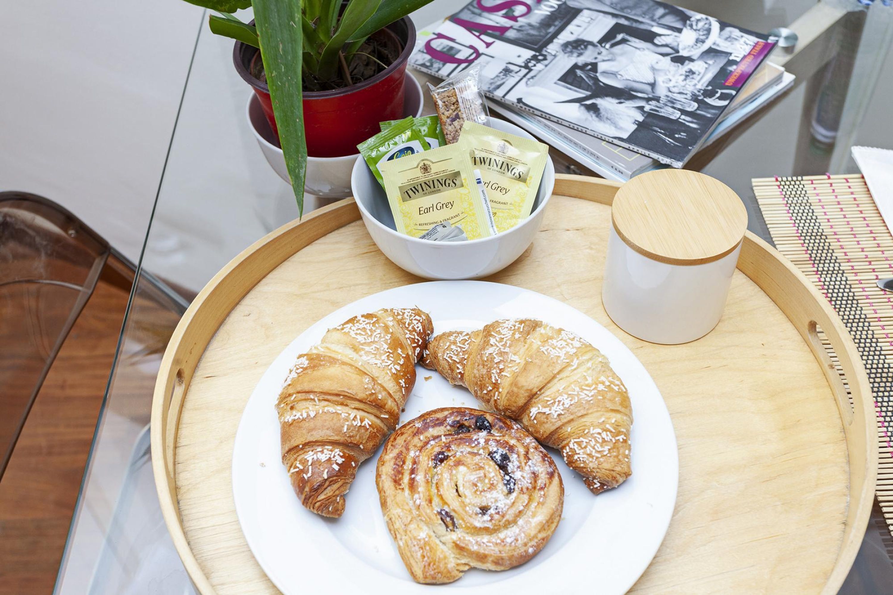 A tray with croissants, a plate, and a cup on a wooden table.