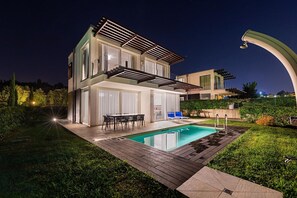 A modern two-story house with a swimming pool, outdoor seating, and a well-lit patio area. - Lake Sunbeam Villa by Wonderful Italy (Manerba del Garda)