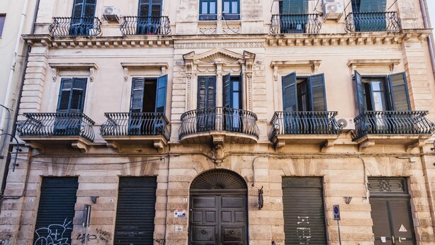 A multi-story building with balconies, a central entrance, and closed shutters. - Grimaldi 8 Apartment by Wonderful Italy (Catania)