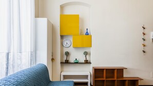 A room with a blue sofa, a white bench, a wooden table, and yellow storage units. - Grimaldi 8 Apartment by Wonderful Italy (Catania)