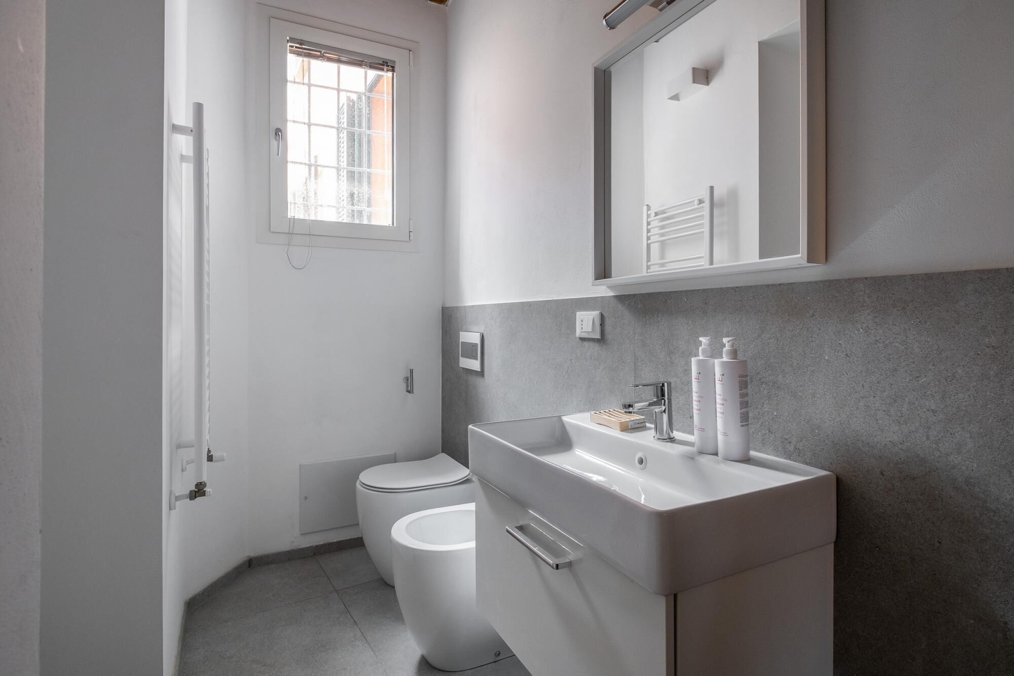 A modern bathroom with a toilet, a sink, and a window.