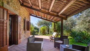 An outdoor patio with wicker furniture, a stone wall, and a wooden pergola. - Villetta Rosamarina by Wonderful Italy (Cefalù)