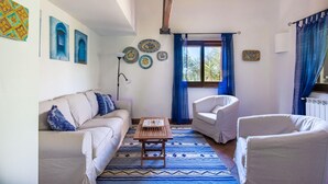 A living room with a beige sofa, two white armchairs, a wooden coffee table, and a patterned rug. - Villetta Rosamarina by Wonderful Italy (Cefalù)