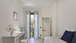 A bedroom with a bed, a bedside table, a mirror, a dresser, and a door leading to a balcony. - Shelley Apartments - Tree by Wonderful Italy (Genoa)