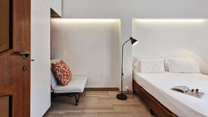Une chambre à coucher avec un lit, une chaise, une lampe sur pied et une porte.