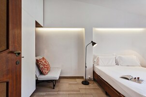 Una camera da letto con un letto, una sedia, una lampada da terra e una porta.