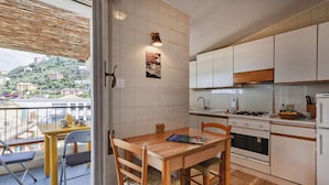 Une cuisine moderne avec des meubles blancs, une table à manger en bois et une vue sur une colline.