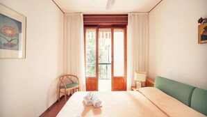 Habitación de hotel con cama, una silla, una lámpara y vistas al exterior.