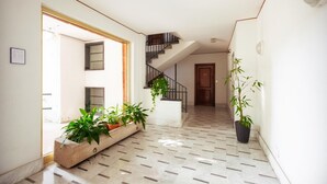 Un pasillo con piso de baldosas, una escalera y plantas en macetas.