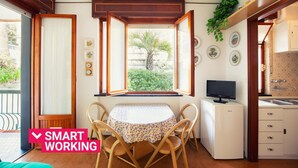 Cocina compacta con comedor, televisor y ventana con persiana abierta.