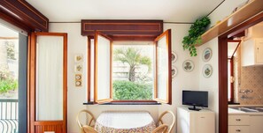 A compact kitchen with a dining area, a TV, and a window with an open shutter. - A due Passi dal Mare by Wonderful Italy (Sanremo)