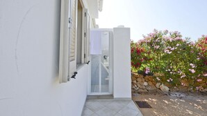 A white building with a glass door leading to a covered outdoor area.
