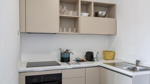 Eine kompakte Küche mit Einbauofen, Spüle und einer Arbeitsplatte mit Wasserkocher, Kaffeemaschine und einer Körbe.