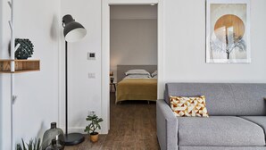 Ein modernes Wohnzimmer mit einem grauen Sofa, einer Stehlampe und einem Bild an der Wand.