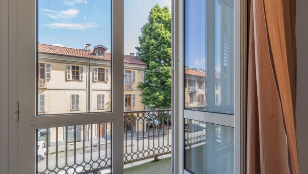 A balcony with a metal railing, a view of buildings, and a tree. - Ai Piedi Della Collina by Wonderful Italy (Turin)