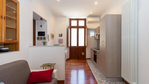 A compact living space with a sofa, a small table, a cabinet, and a kitchen area with a radiator. - Ai Piedi Della Collina by Wonderful Italy (Turin)