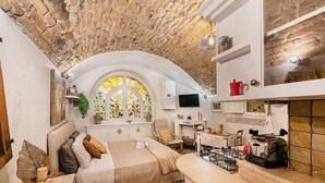 A cozy room with a bed, a desk, a stove, and a large window with stained glass. - C era una Volta in Centro by Wonderful Italy (Desenzano del Garda)