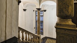 A grand staircase with ornate balustrades and a view of a window with barred glass. - Fancy Apartment in Palazzo Grimaldi by Wonderful Italy (Genoa)