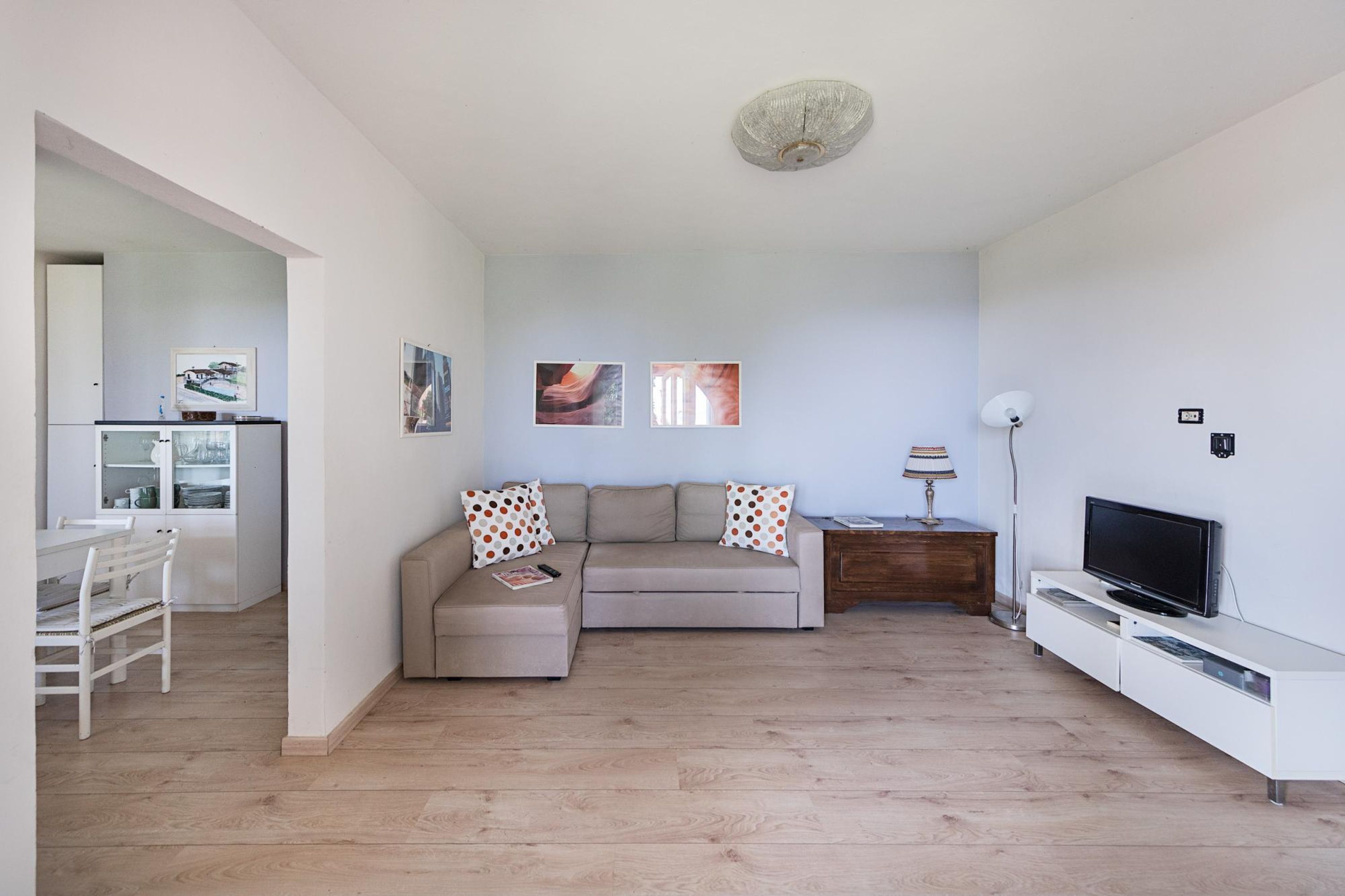 Uma sala de estar moderna com sofá, televisão e área de jantar com mesa e cadeiras.