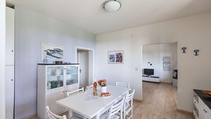 A compact kitchen with white cabinetry, a dining table with chairs, and a small island with a vase of flowers. - Casa Alba con Giardino e Patio by Wonderful Italy (Lonato del Garda)
