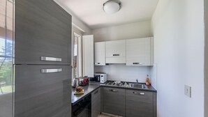 A modern kitchen with grey cabinets, a stainless steel refrigerator, a microwave, and a gas stove. - Casa Alba con Giardino e Patio by Wonderful Italy (Lonato del Garda)